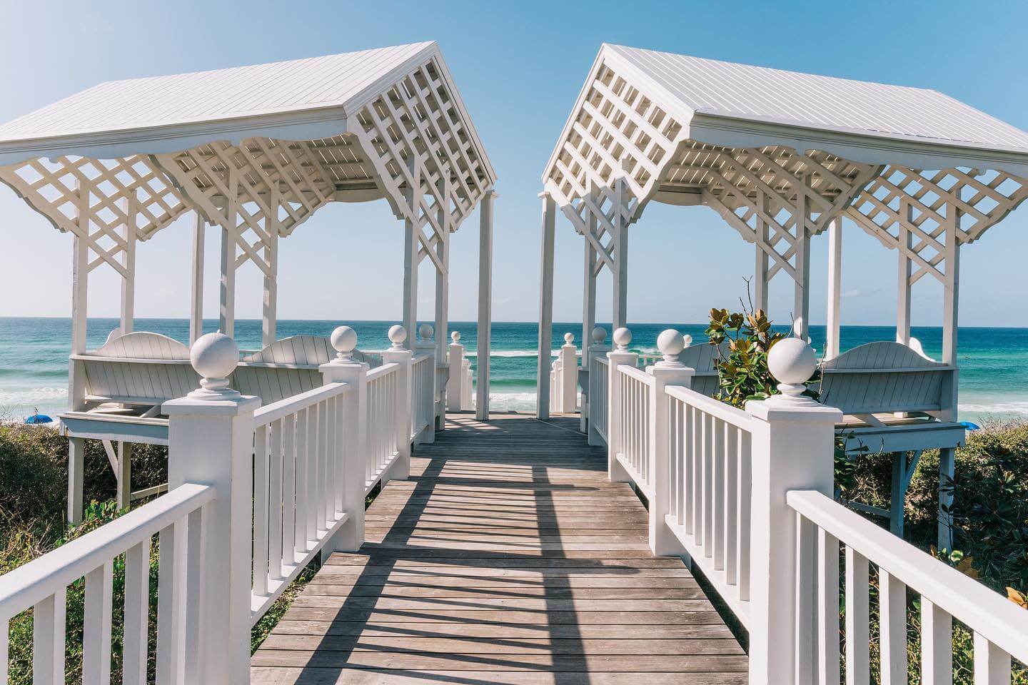 Two white gazebos leading to the beach.