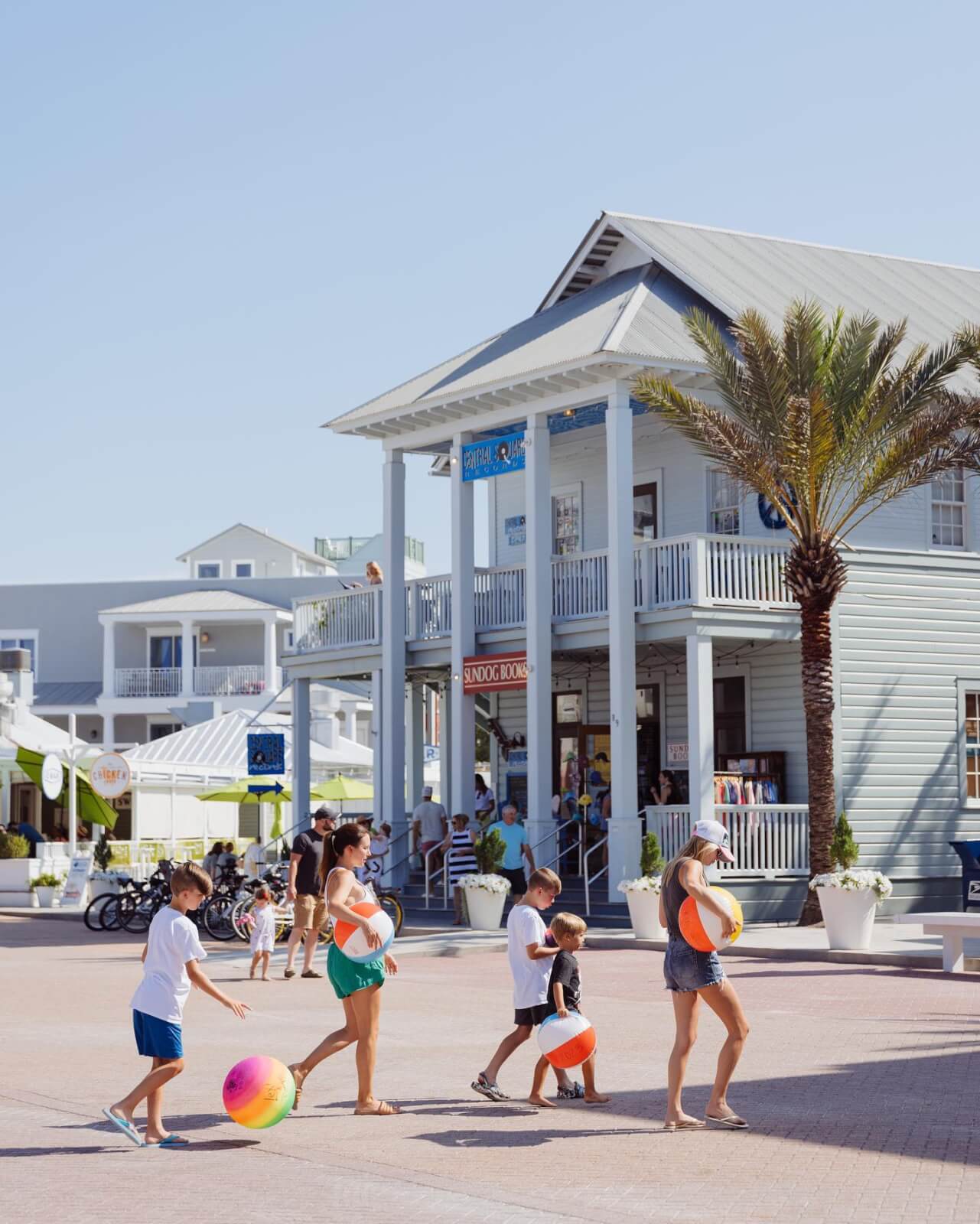 A group of children playing on a beach in front of a building.