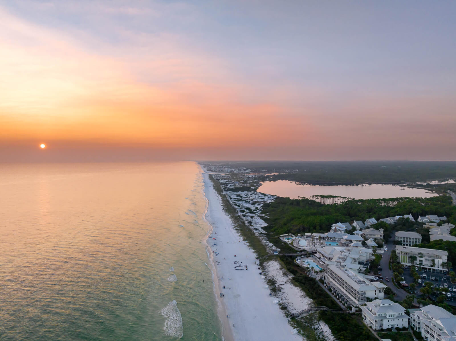 An aerial view of a beach and ocean at sunset.