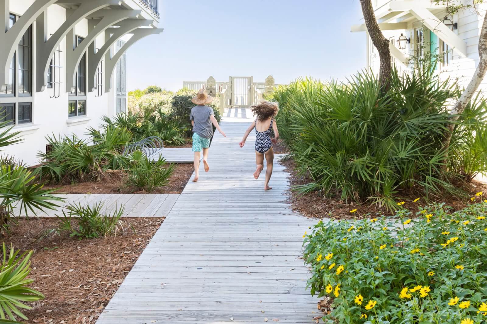 Two children running down a wooden walkway in front of a house.