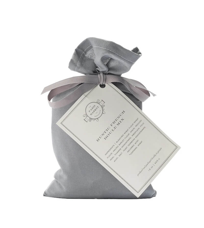 A gray fabric pouch with a tied ribbon and a tag labeled "Rustic French Lavender Sachet" offers the perfect touch of elegance