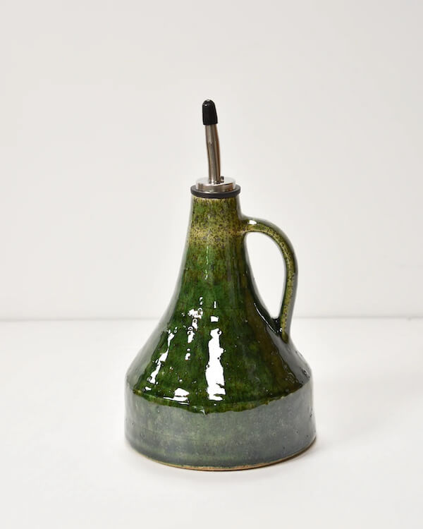 A green ceramic bottle with a handle and a metal spout, set against a plain white background.