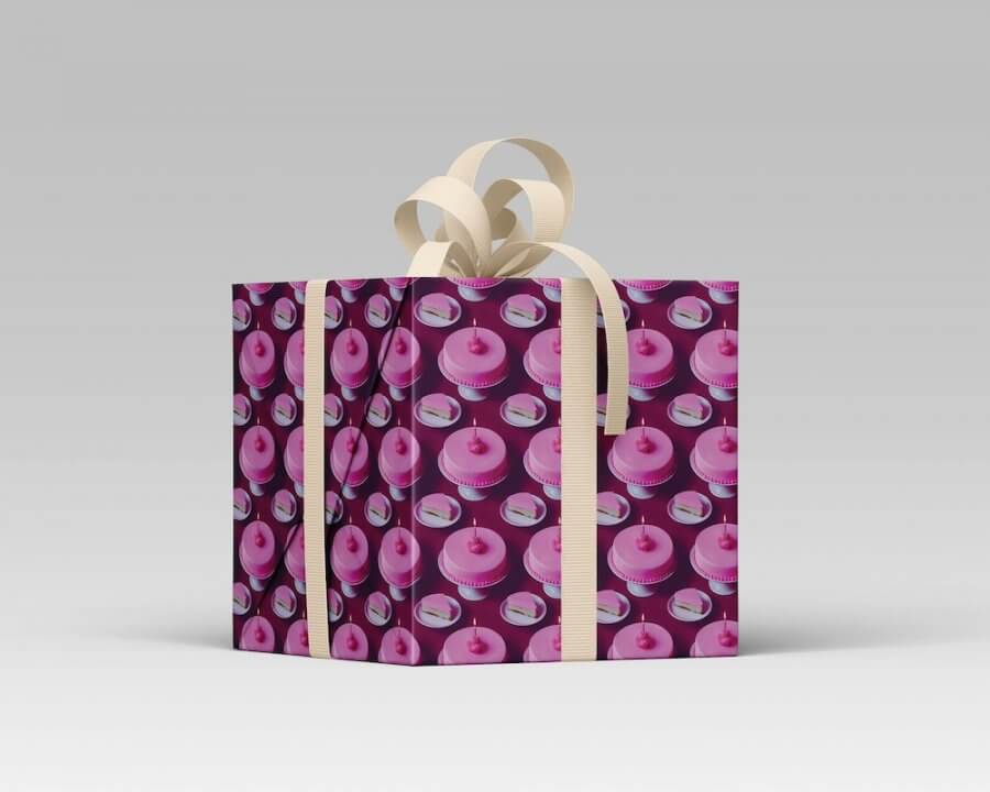 A delightful gift box wrapped in playful pink and purple cake-patterned paper, tied with elegant beige ribbon bows on top, perfect for making holidays extra special. Crafted with care by skilled Southern paper makers, this charming package adds a touch of joy to any celebration.