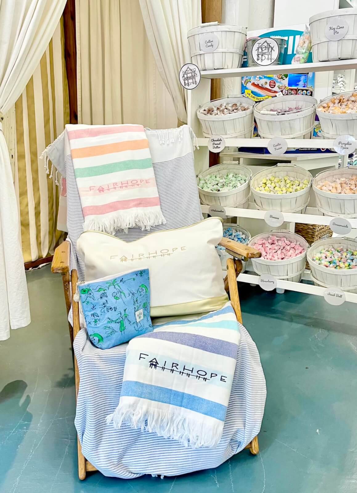 A chair with striped blankets and a pillow is displayed beside shelves filled with baskets of candies.