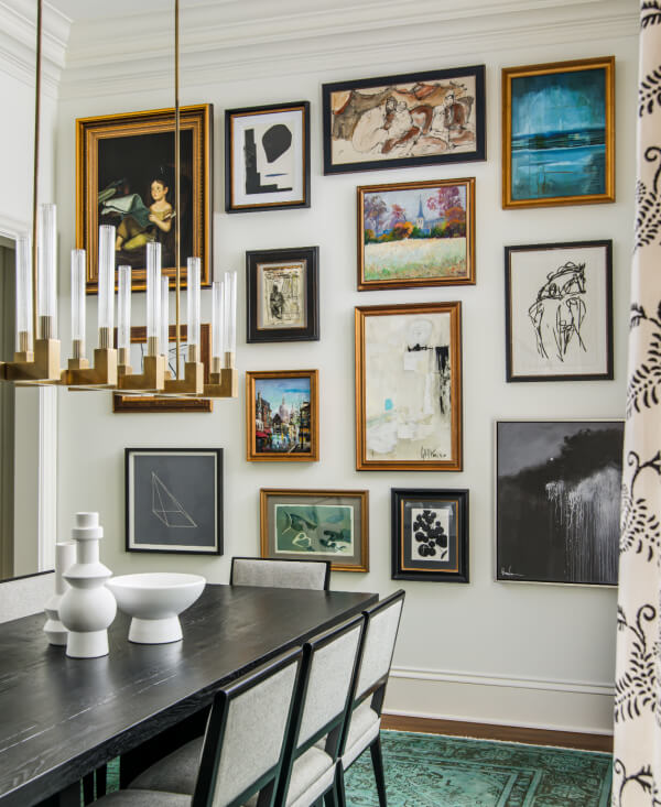 The dining room, featuring a dark table and upholstered chairs beneath a modern chandelier, embraces 2025 interior design trends. The walls showcase a gallery of framed artworks with patterned curtains adding a glimpse of style.