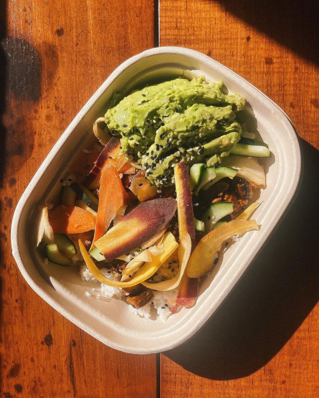 salad in a rectangular cardboard container on a wooden table