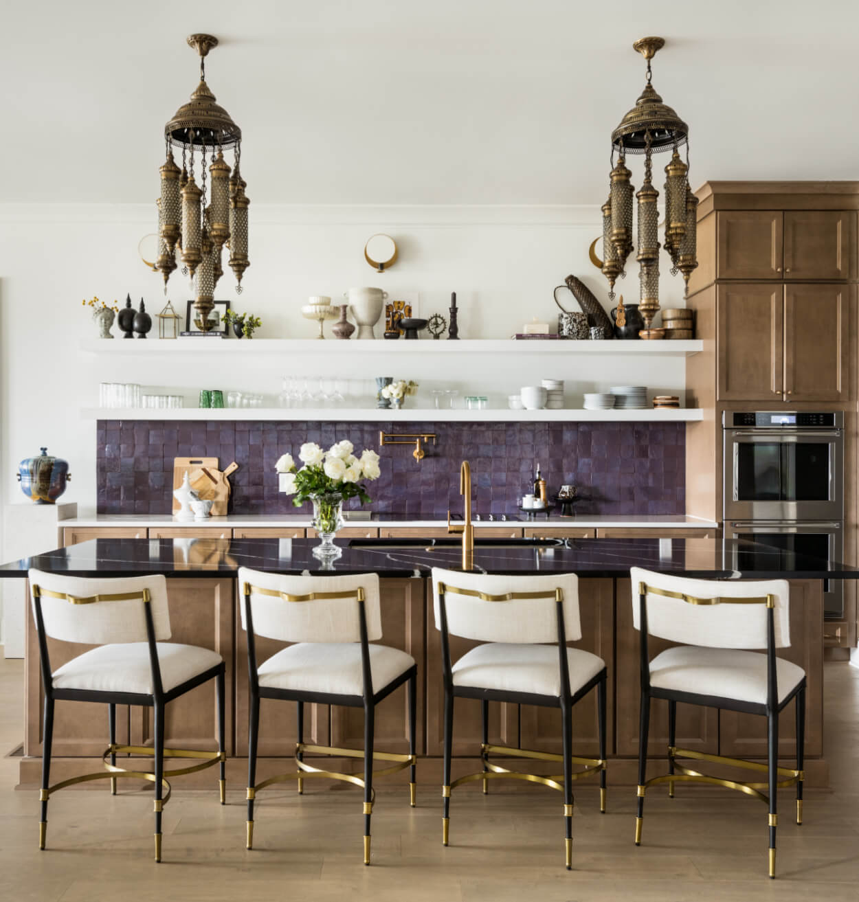 Elegant kitchen interior with bar stools, wooden cabinetry, and pendant lighting.