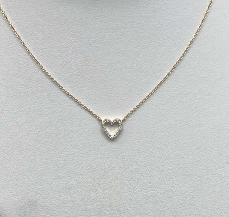 Discover the allure of a gold necklace featuring a delicate heart-shaped pendant, artfully showcased on a white background. Perfect for adding a touch of elegance to your January wardrobe, this exquisite piece is among the finest Nashville FINDS.