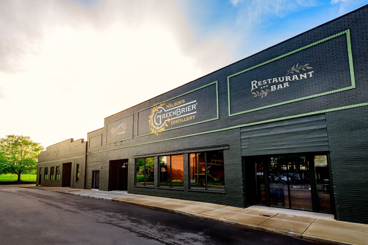 Exterior view of Green Brier Distillery and restaurant/bar. The stunning dark green brick facade stands proudly against a clear sky background, inviting visitors to explore its rich heritage and modern allure.