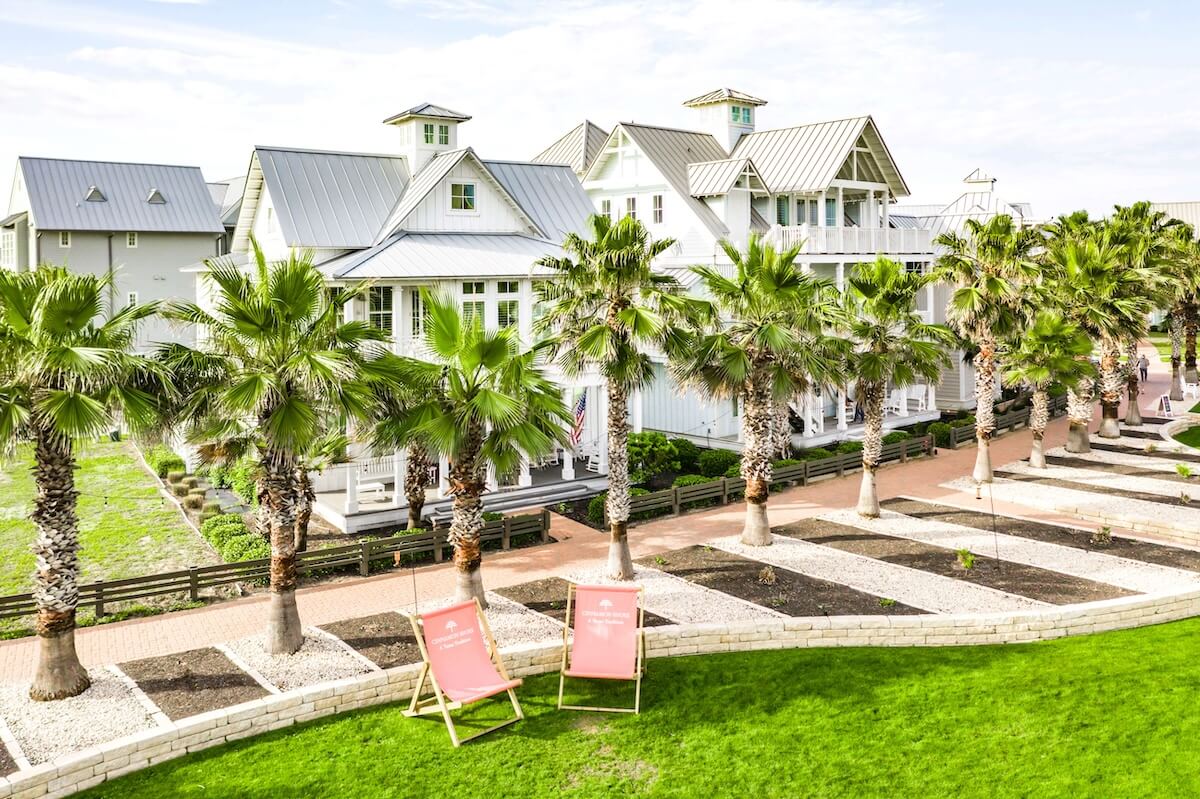 A lawn with palm trees and a house in the background.