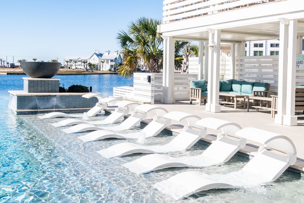 A pool with lounge chairs and a view of the water.