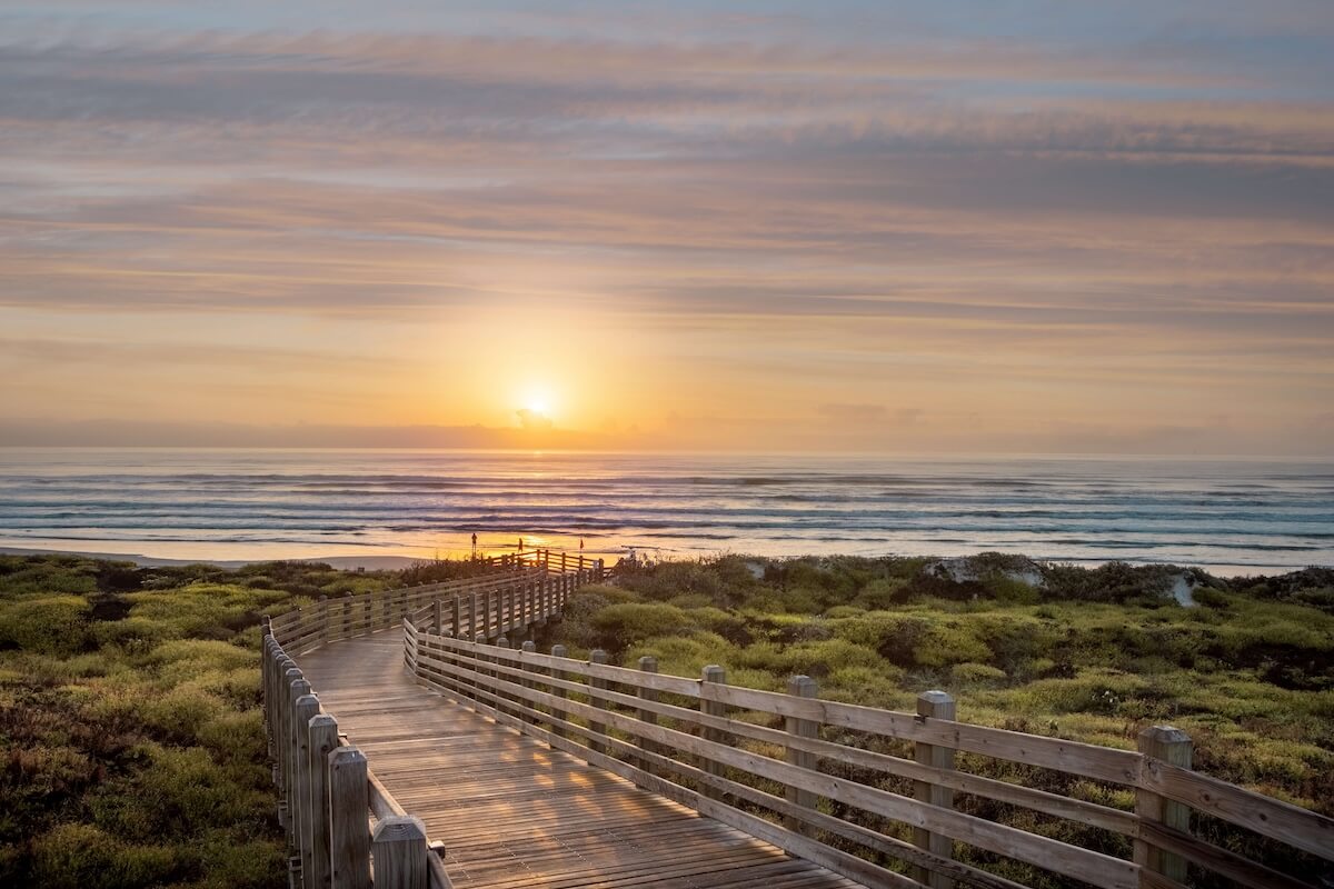 A wooden walkway leading to the beach at sunset.