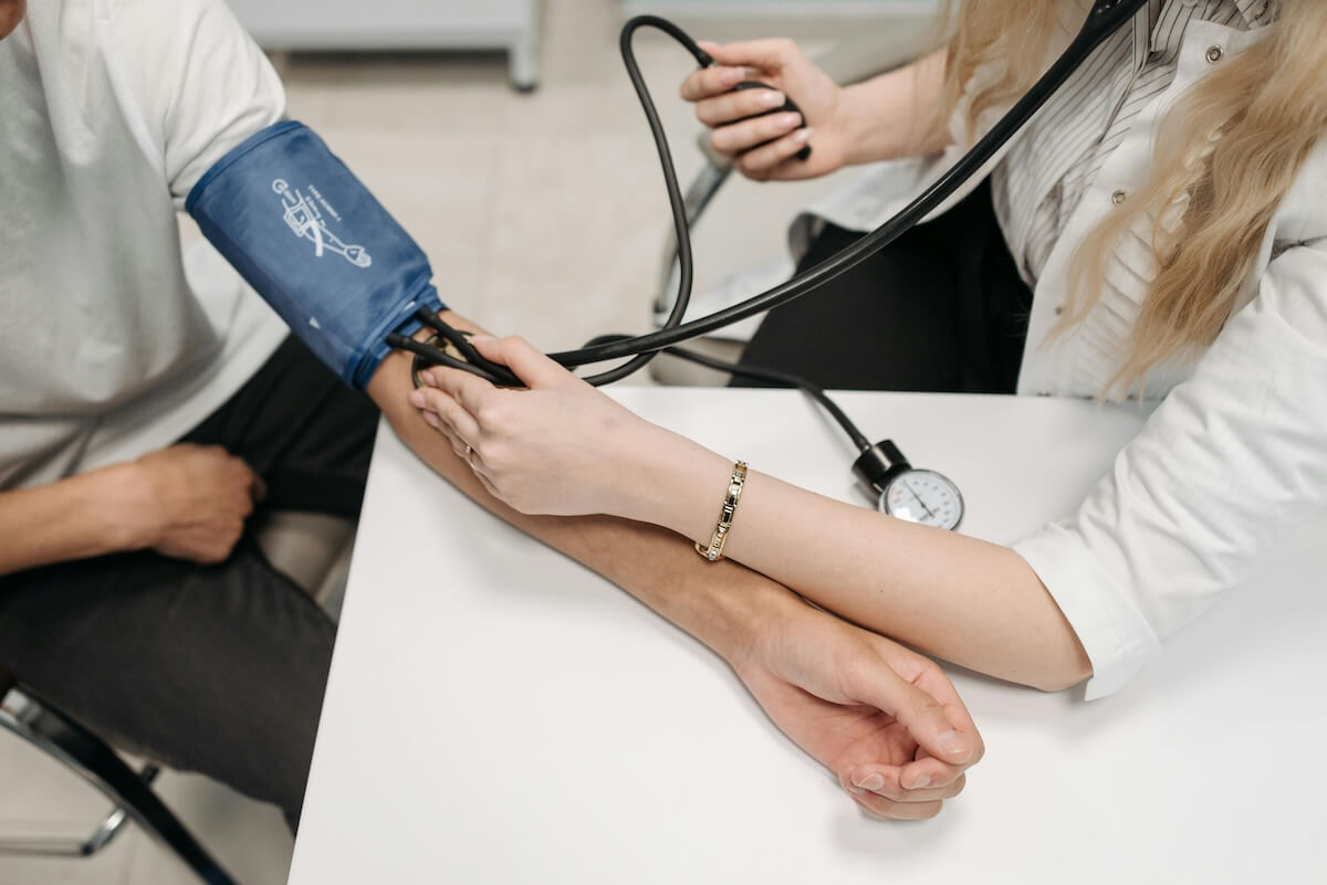 In a clinical setting, a healthcare professional measures a patient's blood pressure using a sphygmomanometer, addressing any questions about maintaining healthy levels.