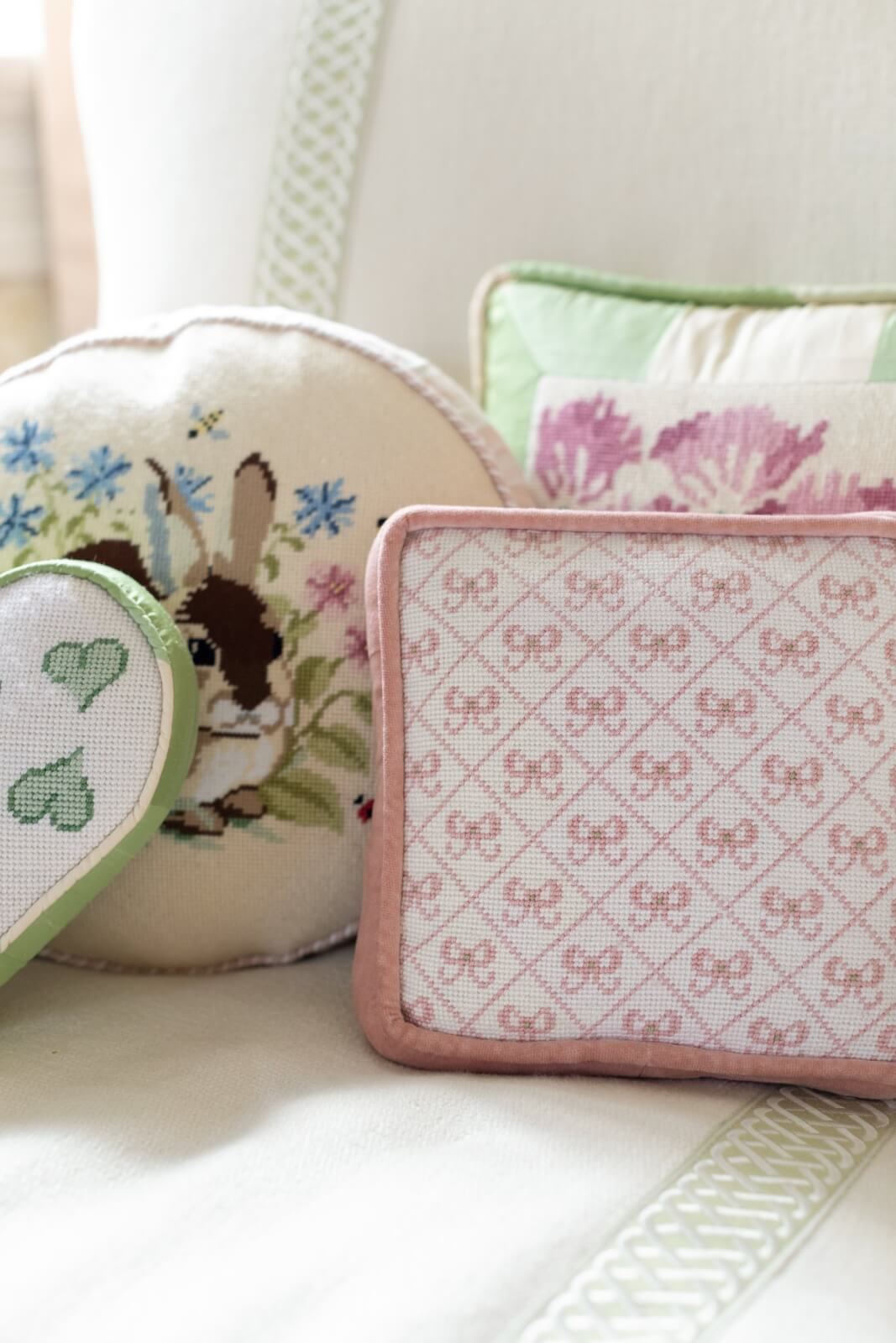 Cushions on a chair, including one with a floral bunny design and another with a pink patterned print, evoke the charm of a New Orleans home.