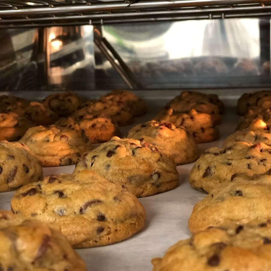 Rows of freshly baked cookies with chocolate chips line the baking tray, ready to be enjoyed or sent far and wide by cookie companies that ship.