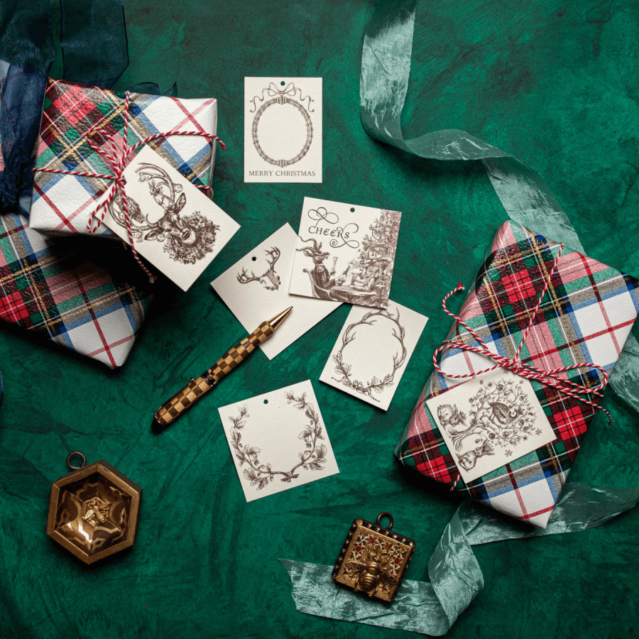 Wrapped gifts with plaid patterns and tied with strings, surrounded by decorative cards and a pen, set on a green background adorned with gold ornaments, bringing extra charm to your holiday celebrations.