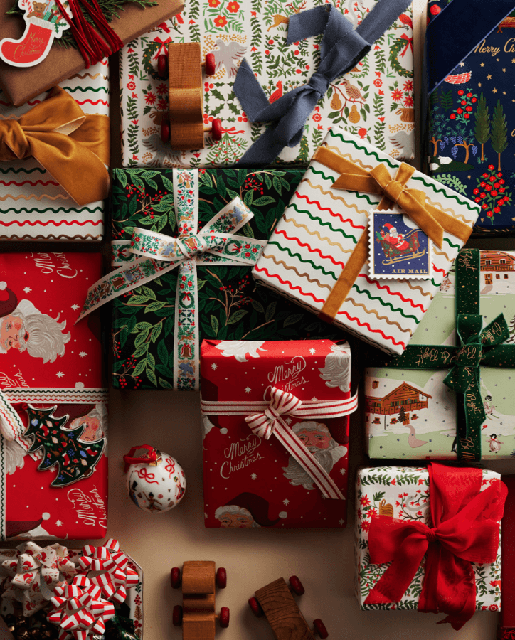 Various Christmas gifts wrapped in festive paper with ribbons and bows, surrounded by holiday decorations, including a small toy and an ornament. Celebrate the holidays with beautifully wrapped presents that capture the season’s joyful spirit.