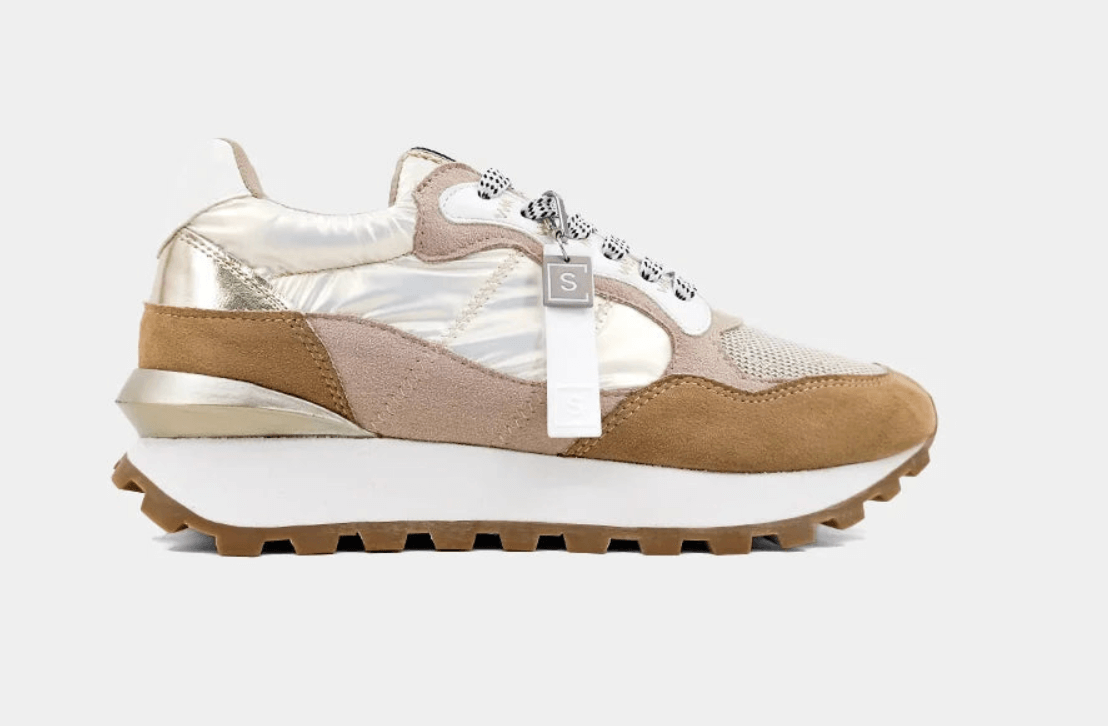 Beige and metallic gold sneaker. It features a thick white sole, brown tread, mesh, and suede-like materials, complete with a decorative tag.