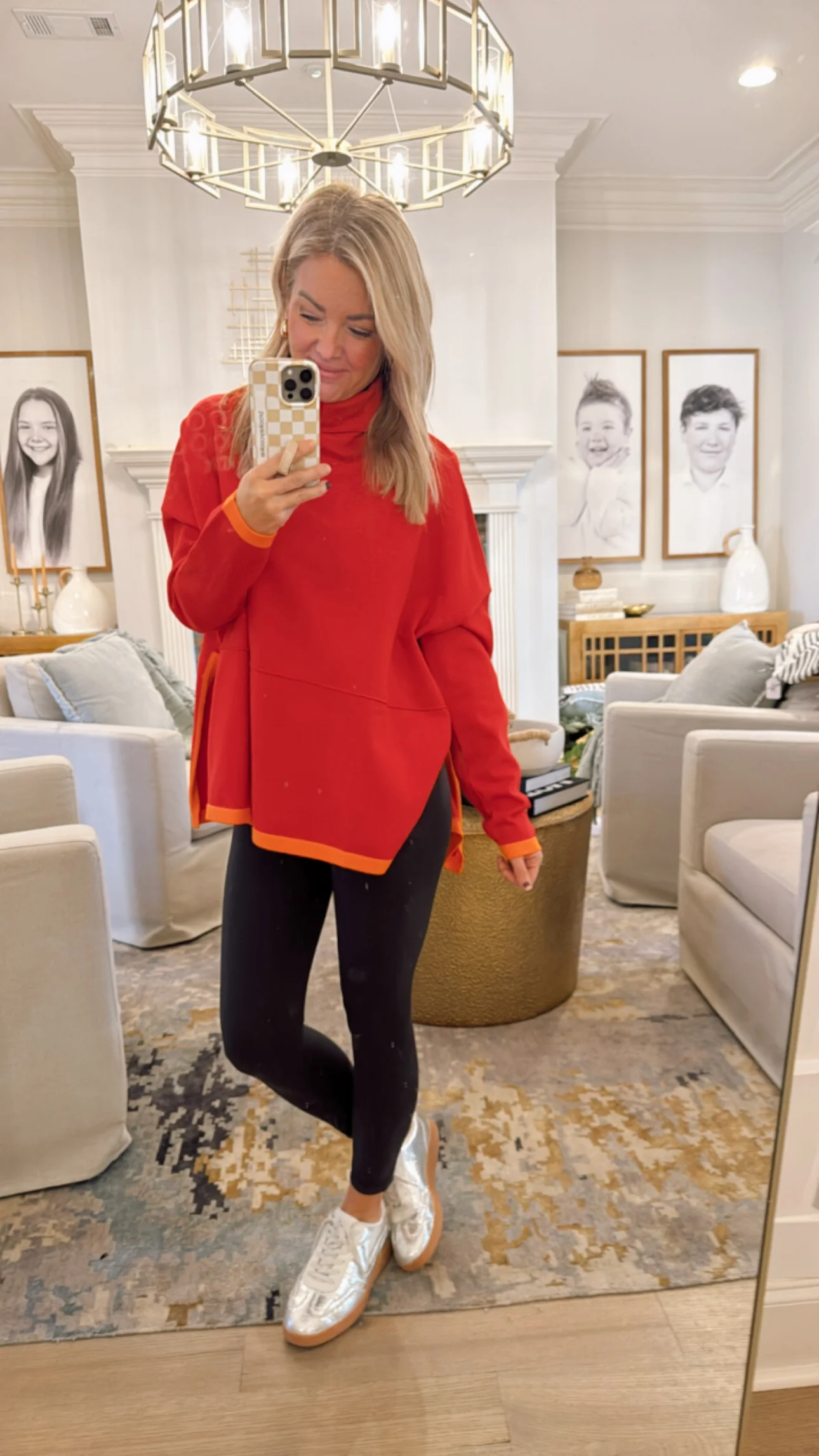 Woman in a red turtleneck sweater taking a selfie in a full-length mirror.