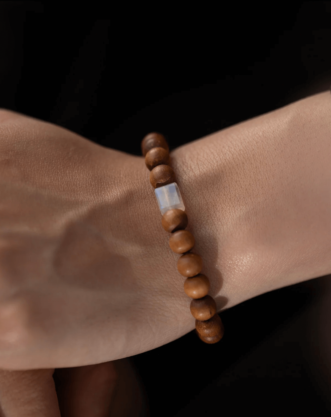 Wooden bead bracelet, with a single white rectangular bead at its center, rests against the dark backdrop.