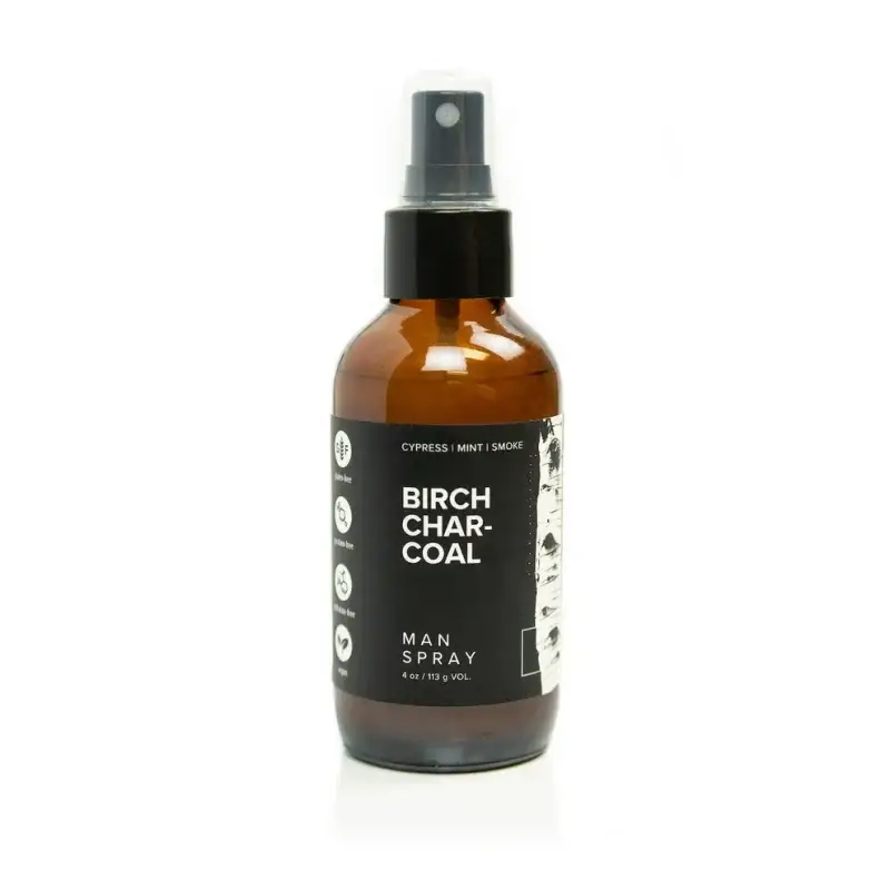 A bottle of Birch Charcoal man spray. The amber-colored bottle, with its sleek spray nozzle, exudes hints of cypress, mint, and smoke—a perfect blend for the discerning gentleman.